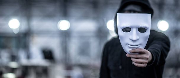 Μυστήριο άνθρωπος hoodie κρατώντας λευκή μάσκα - Φωτογραφία, εικόνα