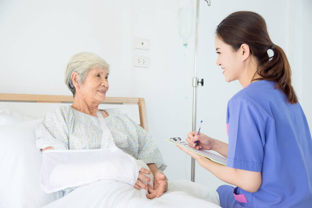 Gyönyörű nővér látogató magas rangú női beteg kórházban - Fotó, kép
