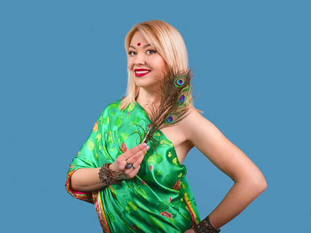 孔雀の羽、ブレスレット、アクセサリーとインドの国民のドレスで美しい笑顔魅力的なヨーロッパのブロンドの女性。旅行 - 写真・画像