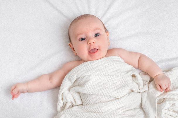 Pasgeboren baby ligt op terug op witte deken - Foto, afbeelding