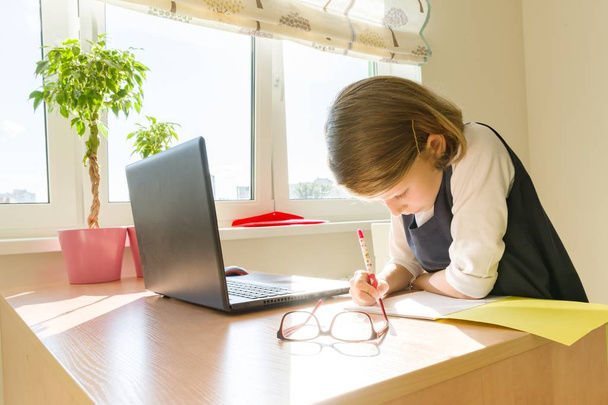 Μαθητρια, κορίτσι 8 ετών, κάθεται στο τραπέζι με τα βιβλία και γράφοντας στο Σημειωματάριο. Σχολείο, παιδεία, γνώση και παιδιά - Φωτογραφία, εικόνα