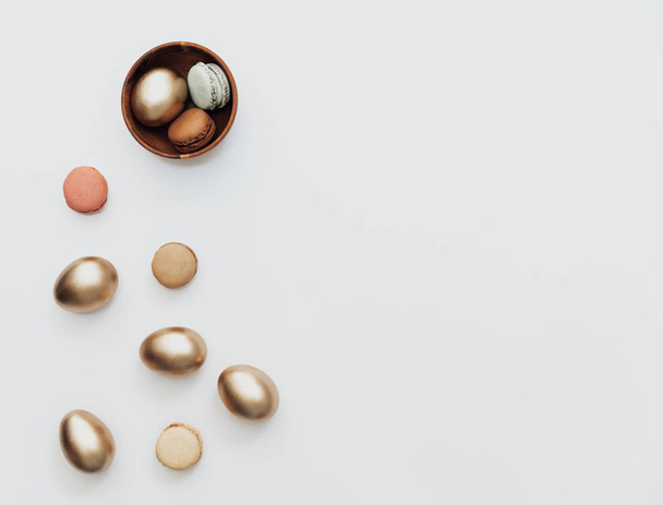 Minimal Flat lay Gold Easter eggs with macaroons on white background. Top view, Still Life Happy Easter holiday concept - Foto, Imagen