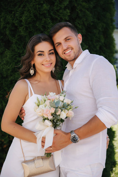 Stylish couple in white clothes walkink in the park. Groom and bride in their wedding day. Charming girl and handsome man - Zdjęcie, obraz