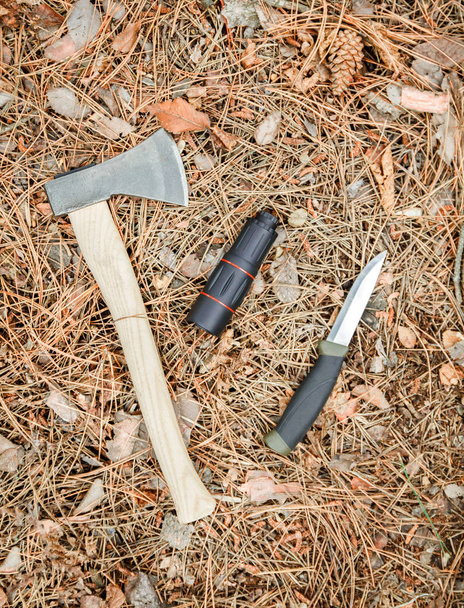 τσεκούρι, μονόκλ και τουριστικά μαχαίρι στο έδαφος που καλύπτεται με πευκοβελόνας - Φωτογραφία, εικόνα