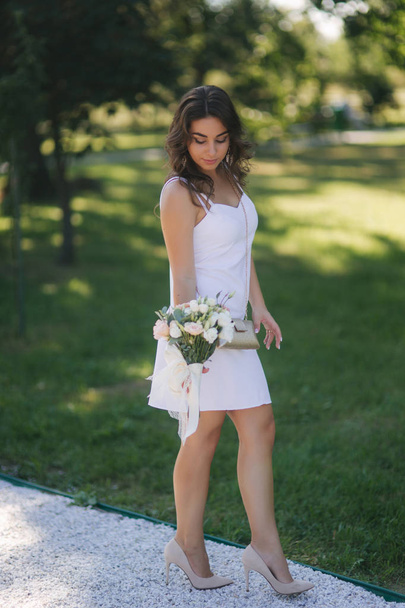 Elegáns nő gyönyörű fehér ruhában, a csokor virágot, séta a parkban. Női modell kívül - Fotó, kép