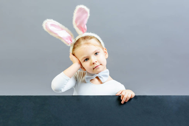 Petite fille en costume de lapin blanc tenant une feuille vide avec de l'espace pour le texte
 - Photo, image