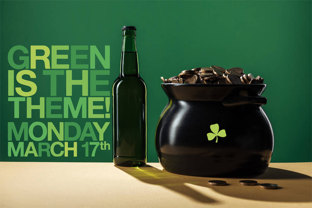 beer bottle and black pot with golden coins near green is the theme lettering on green background - Photo, Image