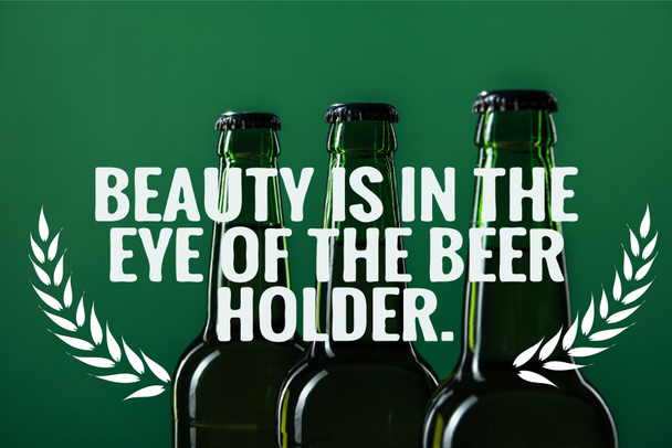 beer bottles near beauty is in the eye of the beer holder lettering on green background - Photo, Image