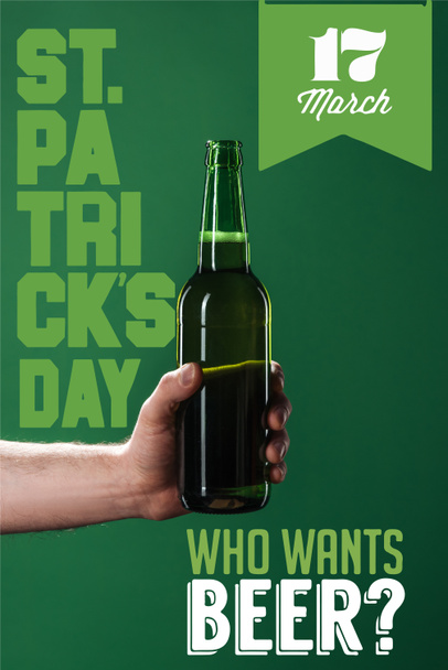 cropped view of man holding beer bottle near who wants beer lettering on green background - Foto, Imagem