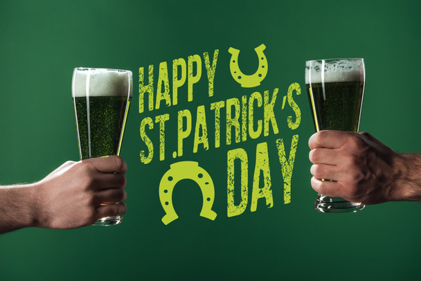 幸せな st 近くの泡とビールのグラスを持って男性のビューをトリミング緑の背景にパトリックの日レタリング - 写真・画像