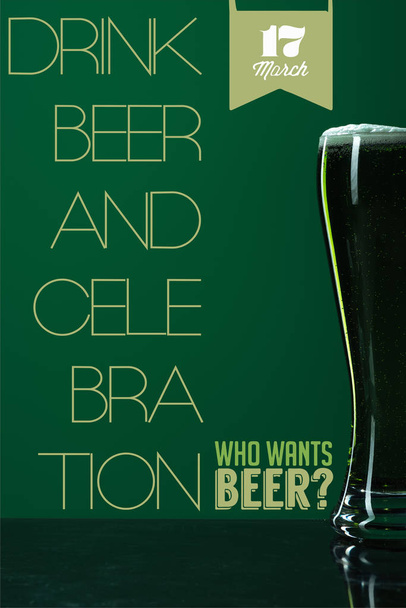 glass of beer with foam near drink beer and celebration lettering on green background - Фото, изображение