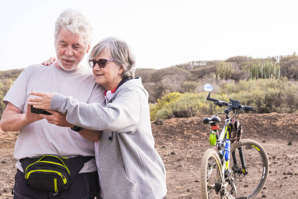 adult senior couple with mountain bikes doing healthy sport outdoor leisure activity together - Photo, Image