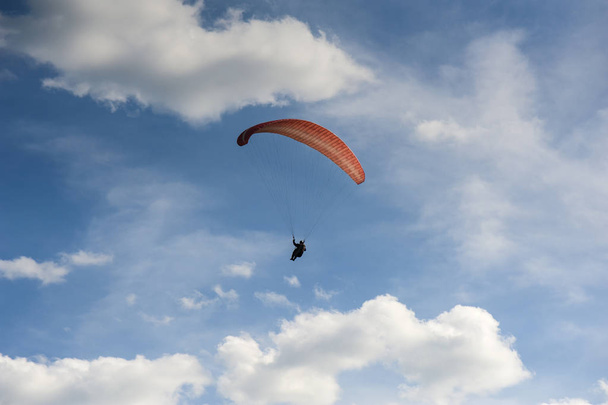 Red paraglider is flying in the blue sky against the background  - Foto, Imagem