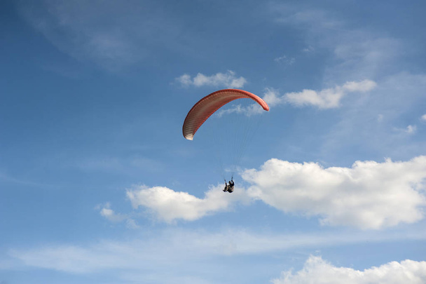 Rode paraglider is vliegen in de blauwe lucht tegen de achtergrond  - Foto, afbeelding