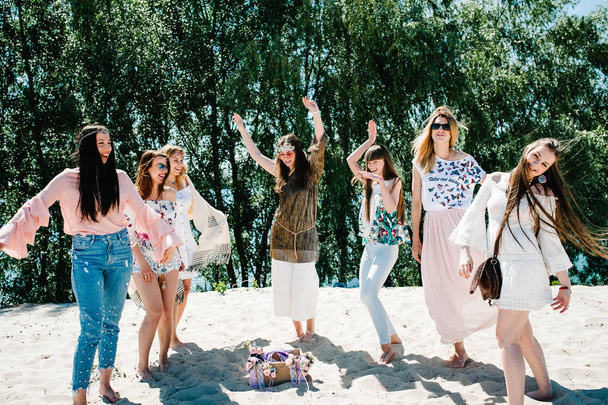 Красиві щасливі стильні сексуальні молоді дівчата розважаються на піщаному пляжі біля прикрашеної коробки з келихом шампанського та квітами. Вечірка в стилі бохо. Дівочий вечір Hen-parts
  - Фото, зображення