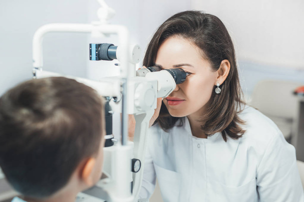 Doctor girlfriend examines eyes  child. Hospital, medical examination, diagnosis. - 写真・画像