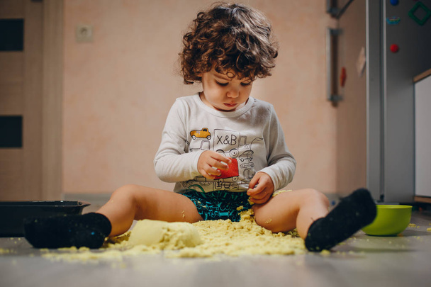 little boy playing with yellow kinetic sand on the floor at home - Zdjęcie, obraz