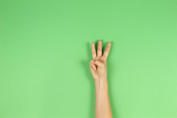 Kid hand showing three fingers on green background - Foto, Bild
