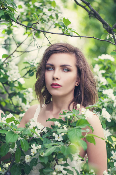 Beautiful young spring woman in white flowers in blooming garden - Foto, immagini