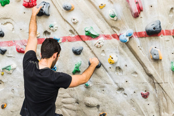 Hombre practicando escalada en roca en paredes artificiales en interiores. Activo
  - Foto, imagen