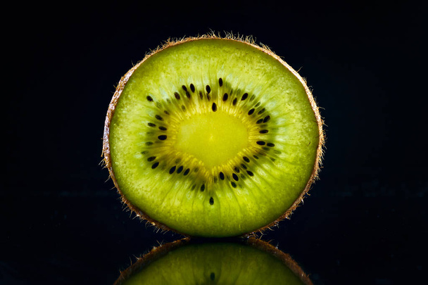 Transparent slice of kiwi on a black background. - Foto, afbeelding