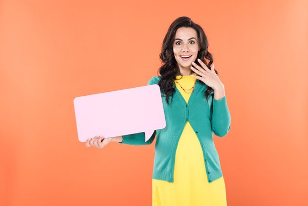 Amazed curly pregnant woman holding speech bubble isolated on orange - Foto, immagini