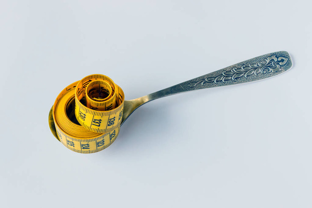 La cinta métrica amarilla enrollada se encuentra en la cuchara. Concepto de dieta saludable, dieta, control y reducción de peso
. - Foto, imagen