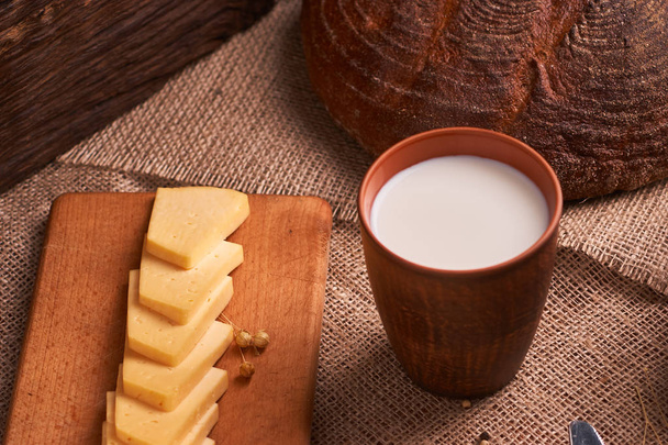 Шматочки сиру на дерев'яному столі біля хліба та молока. місце для тексту
 - Фото, зображення