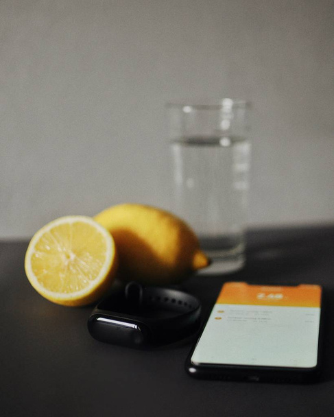 Fitnes tracker avec smartphone couché sur la table avec de l'eau et du citron
 - Photo, image