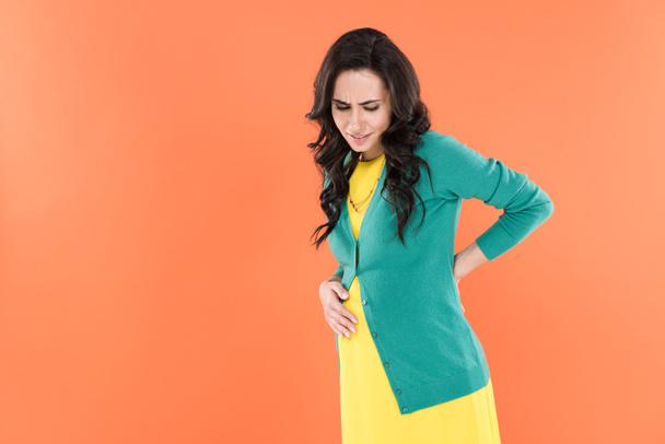 Verärgerte Schwangere mit Rückenschmerzen isoliert auf Orange - Foto, Bild