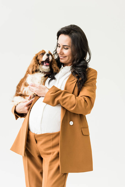 Sonriendo bastante embarazada mujer sosteniendo perro aislado en blanco
 - Foto, imagen