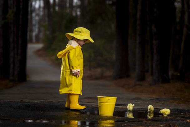 Criança desfrutando da chuva em seus galochas
  - Foto, Imagem