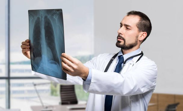 Handsome doctor looking at x-ray - Zdjęcie, obraz