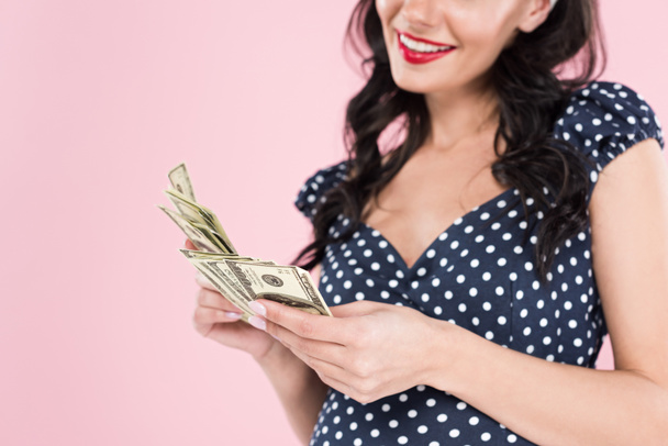 Cropped view of happy pregnant woman holding dollar banknotes isolated on pink - Foto, Bild