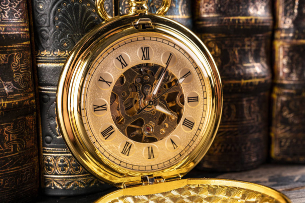 Antique clock on the background of vintage books. Mechanical clo - Foto, Bild