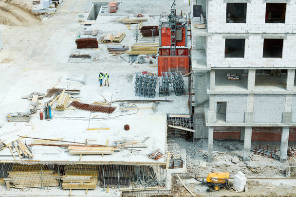 Drone view of unfinished building and two men standing on construction site - Photo, Image