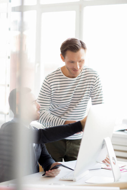 Ritratto di due imprenditori che puntano lo schermo del computer mentre discutono il progetto di avvio in un ufficio moderno
 - Foto, immagini