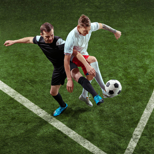 Football players tackling ball over green grass background - Zdjęcie, obraz