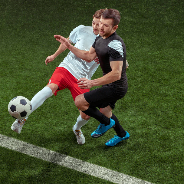 Football players tackling ball over green grass background - Zdjęcie, obraz