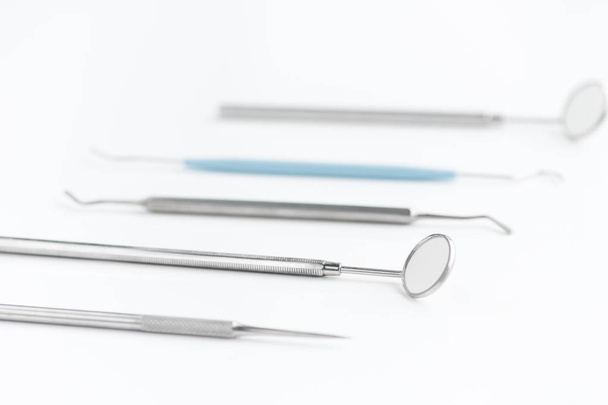 Primer plano de los instrumentos dentales en fila sobre fondo blanco, espejo bucal y otras herramientas
 - Foto, Imagen