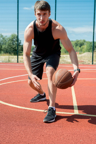 Açık sahada basketbol oynarken yakışıklı kaslı adam lider topu tam uzunlukta portre - Fotoğraf, Görsel