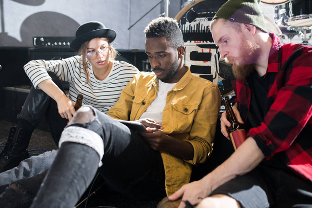 Portrait of three young people using internet and chilling in band rehearsal - Photo, image