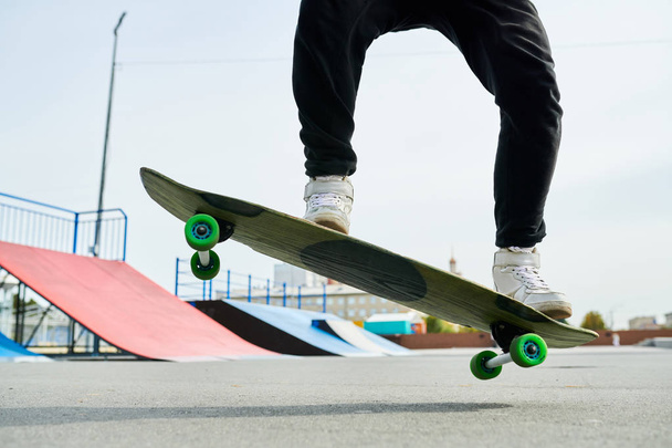 Retrato de seção baixa do jovem contemporâneo fazendo truques de skate ao ar livre no parque extremo, espaço de cópia
 - Foto, Imagem