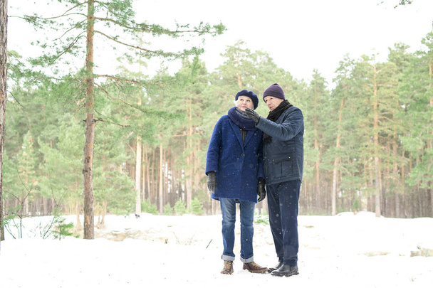 Ganzkörperporträt eines älteren Ehepaares, das während eines Spaziergangs im Winterwald Pause macht, Kopierraum - Foto, Bild