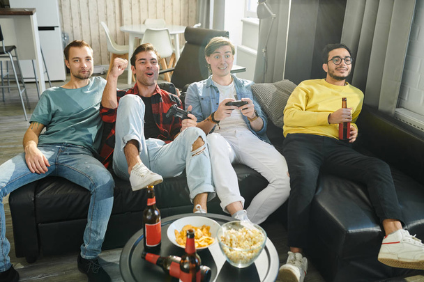 Homme chanceux gagnant dans le jeu, il joue dans des jeux vidéo avec ses amis, ils se reposent et boivent de la bière
 - Photo, image