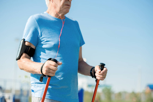 Mid section portrait of active senior man practicing Nordic walking with poles outdoors in park, copy space - Photo, Image