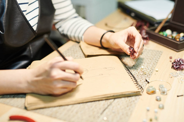 Close-up van onherkenbaar vrouw tekenen schetsen tijdens het maken van prachtige handgemaakte sieraden, kopieer ruimte - Foto, afbeelding