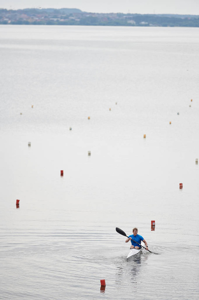 Kaunis näkymä rauhallinen järvi ja meloja kelluva veneessä aikana soutu kilpailu
 - Valokuva, kuva