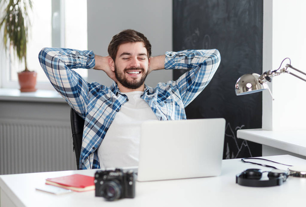 Χαλαρή ευτυχισμένος άνθρωπος στο τραπέζι με φορητό υπολογιστή  - Φωτογραφία, εικόνα