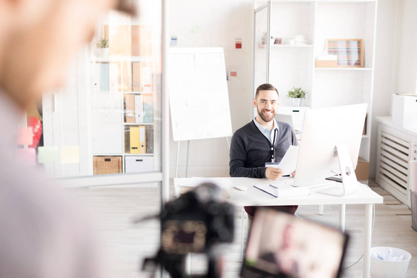 Retrato de homem de negócios sorridente olhando para o fotógrafo enquanto trabalhava na mesa no escritório moderno, espaço de cópia
 - Foto, Imagem